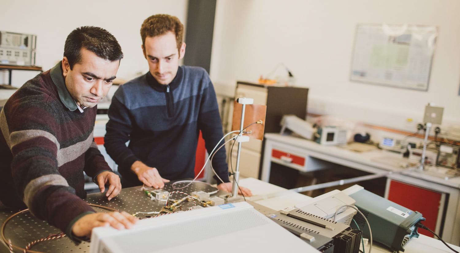 A student working with a member of academic staff in an electronics lab